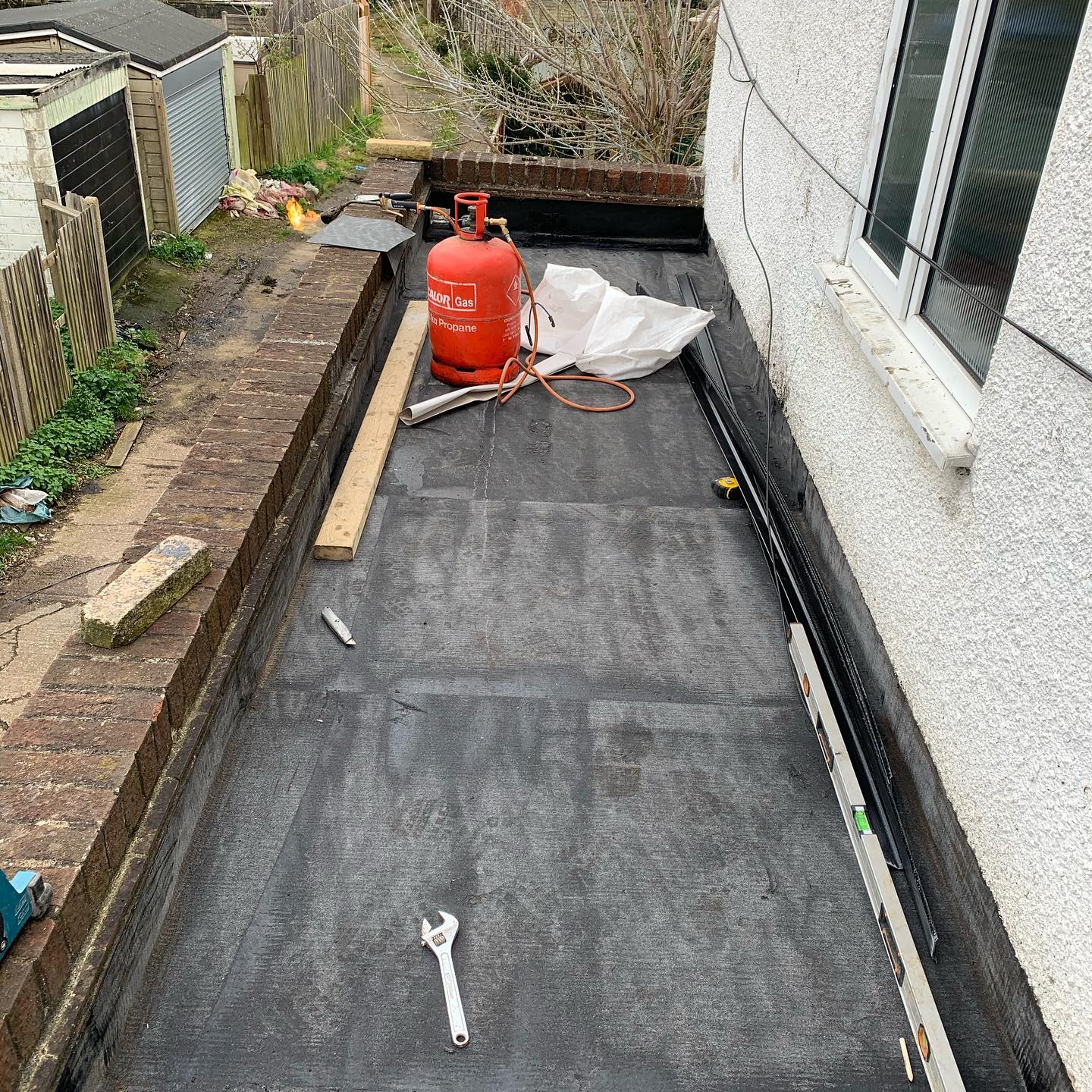 Torch-on felt flat roof underway with propane torch