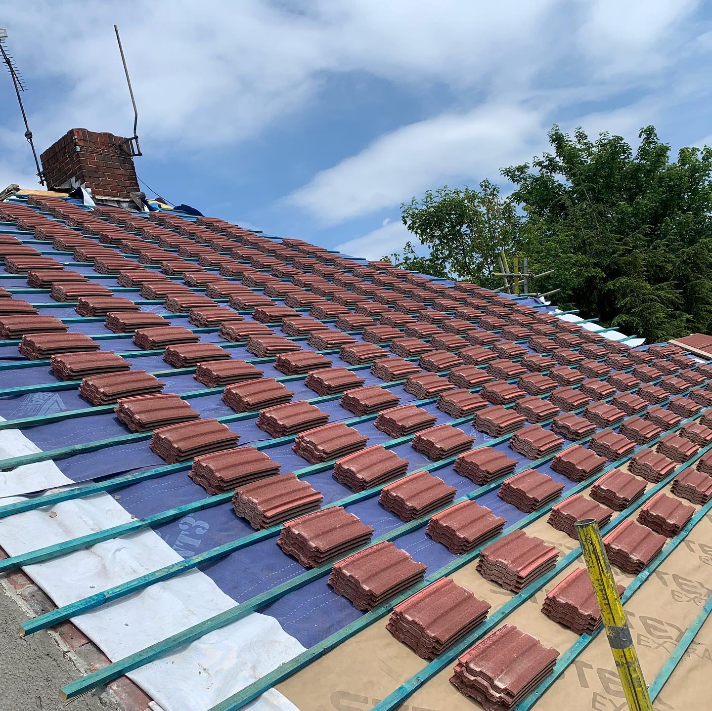 Red roof tiles stacked on battens before laying